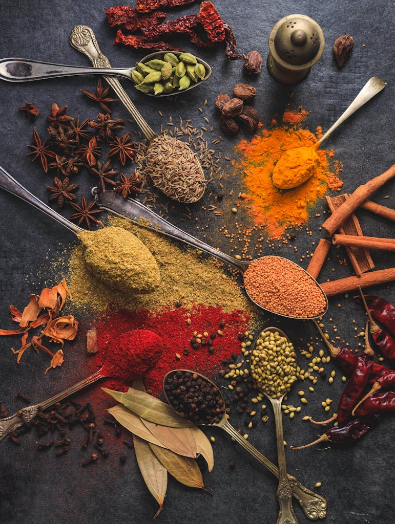 Vibrant array of spices including turmeric, cumin, and chili arranged on a dark surface.